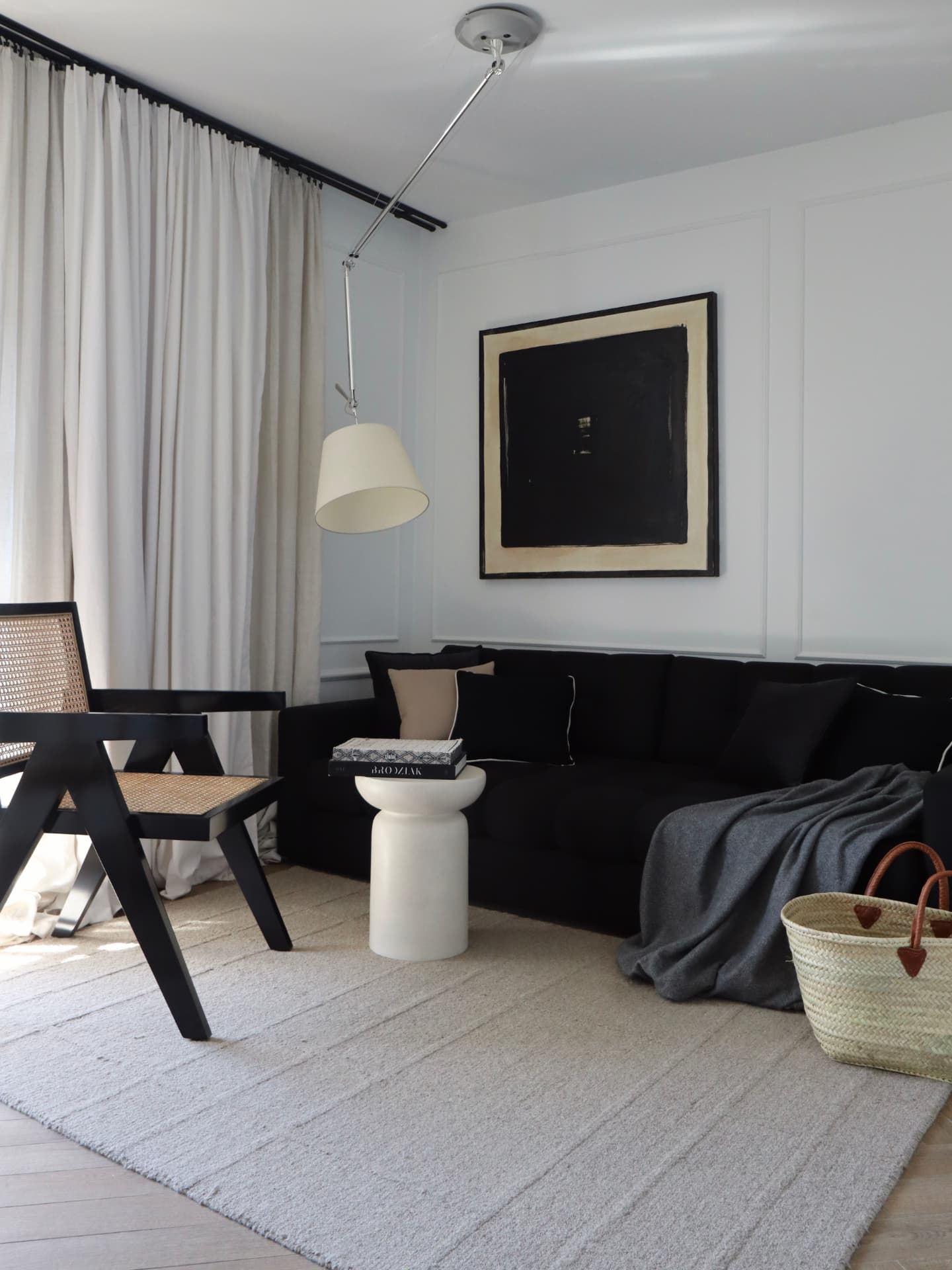 Salon Apartamentu 77 — czarna sofa, obraz i światło dnia