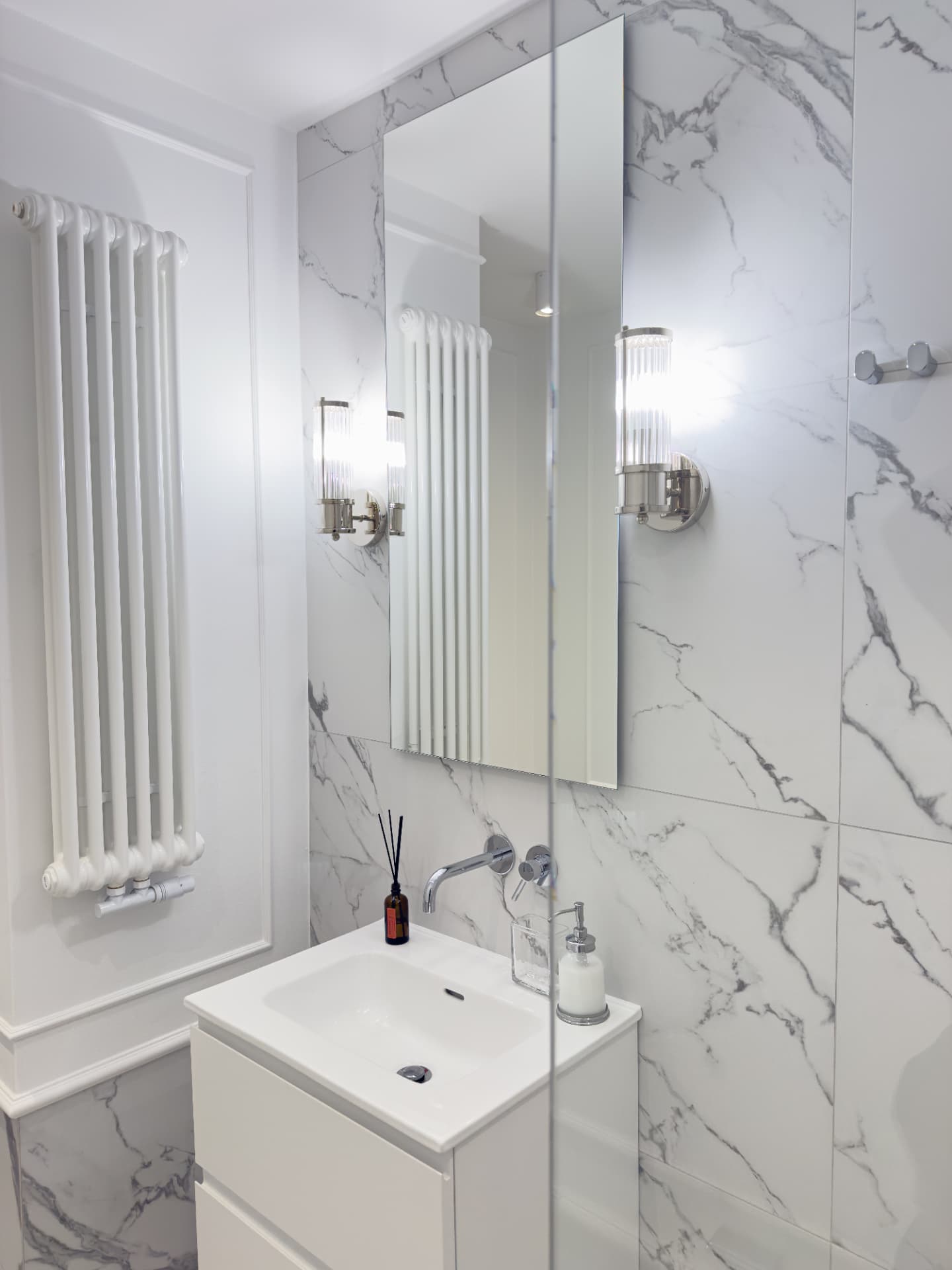 Lustro, kinkiety i umywalka w łazience Apartamentu 77